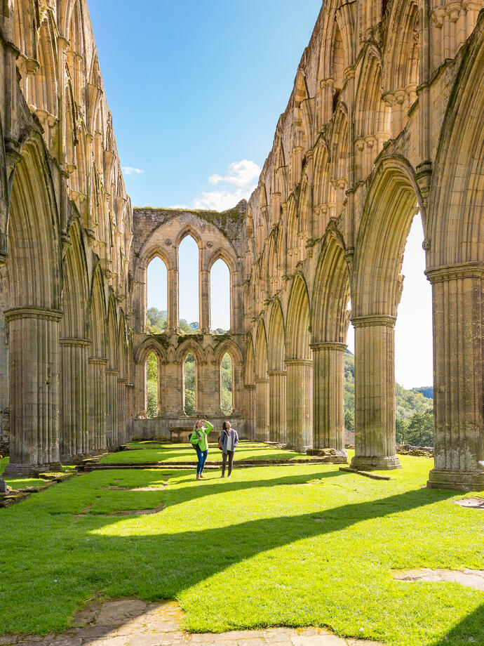 Zwei Menschen, die zwischen den Steinsäulen eines verfallenen Gebäudes im Freien spazieren gehen