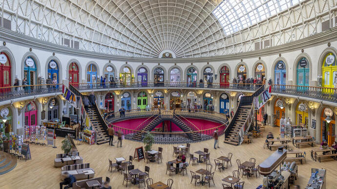 Inside a colourful domed building with people enjoying coffee and walking around the colourful building and stopping for coffee.