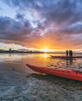 Kayaks and kayakers on beach at sunset. Portobello beach, Edinburgh