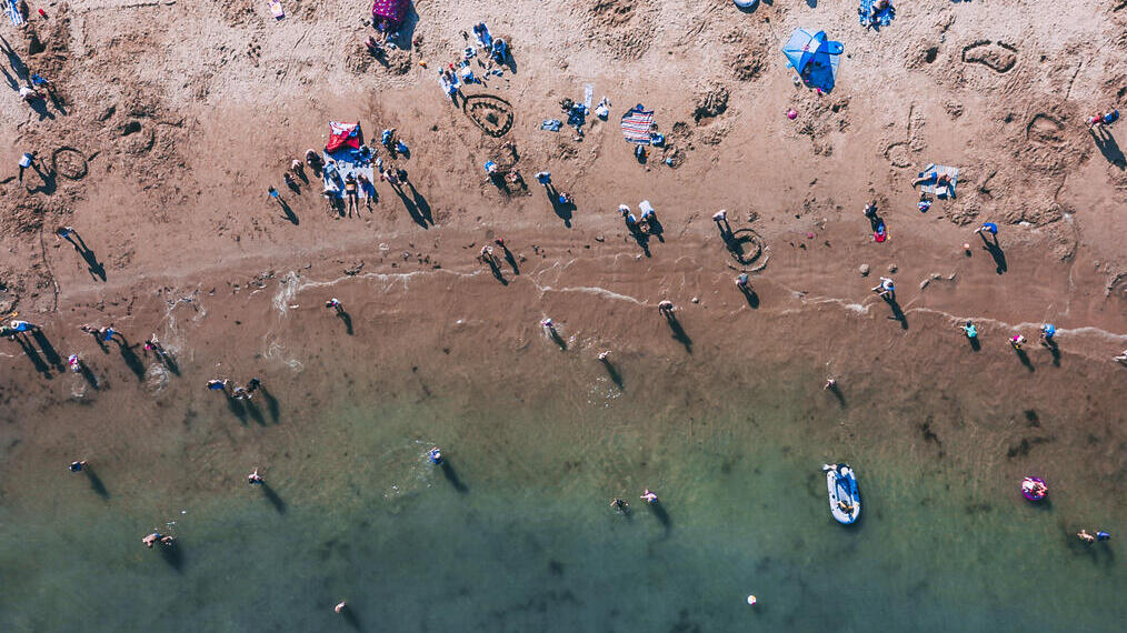 Vista aerea di persone su una spiaggia sabbiosa e che nuotano nel mare