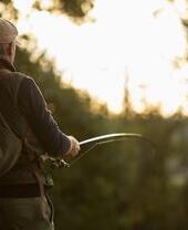 Uomo con zaino che pesca con la mosca