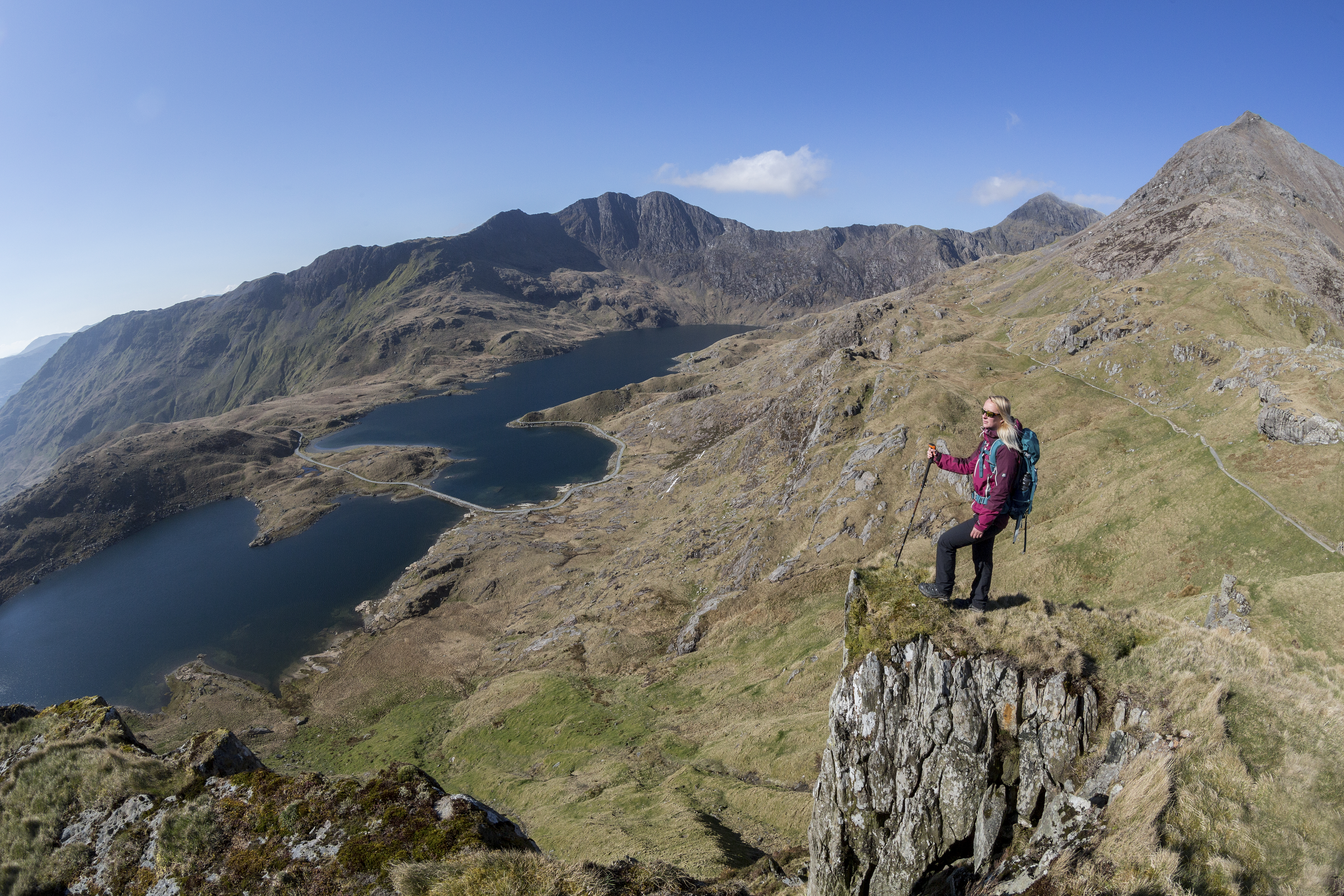 Woman standing on a rock, high above the lake in a valley