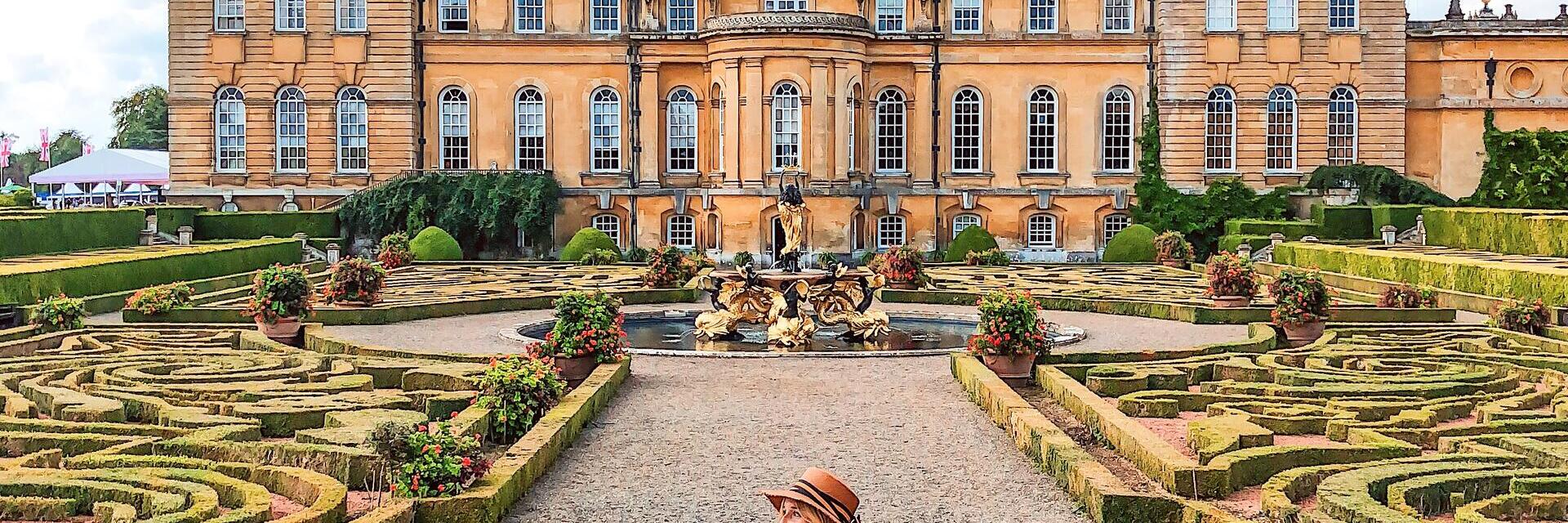 Femme marchant dans les jardins à la française devant un palais