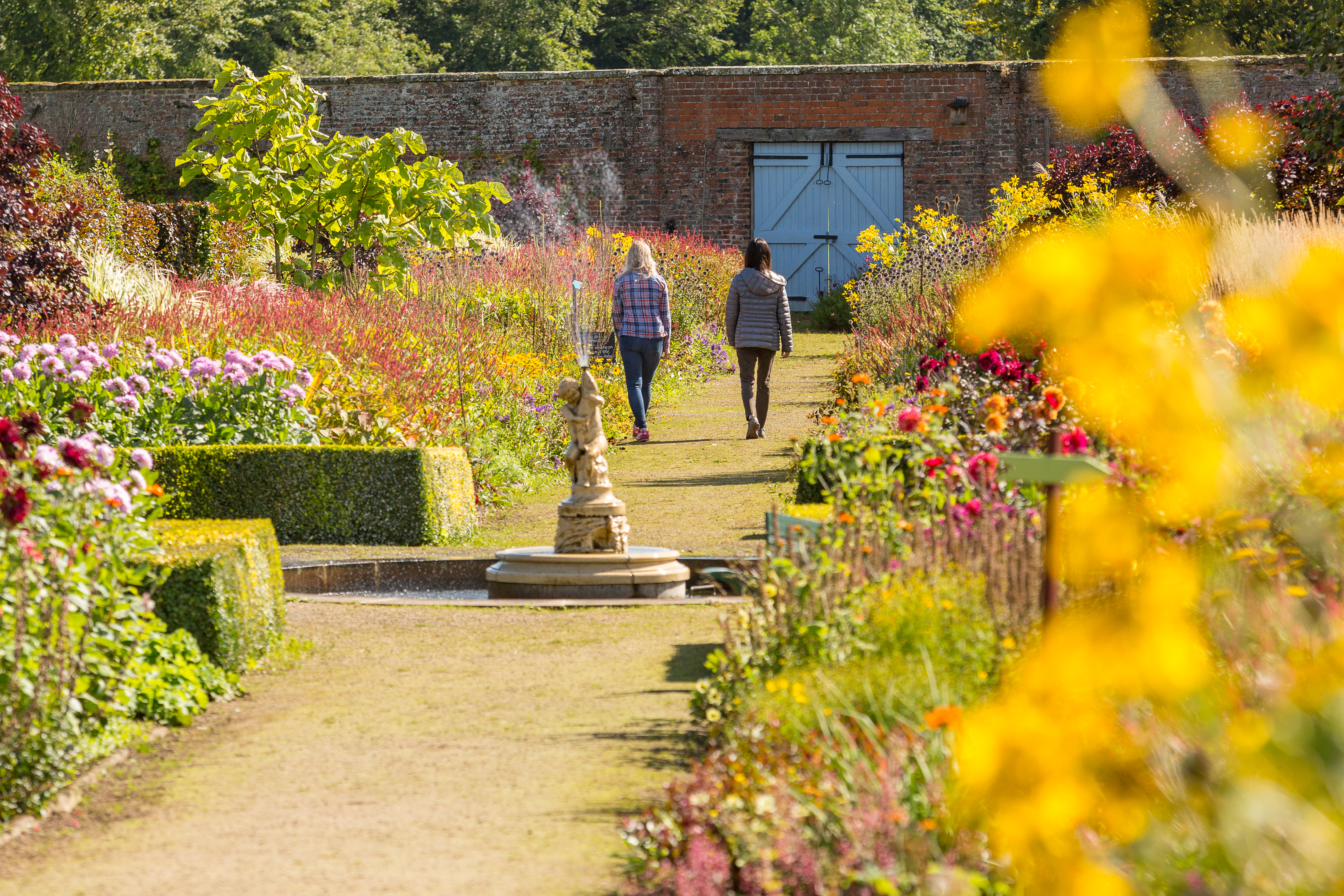 Two female friends walking through a formal garden