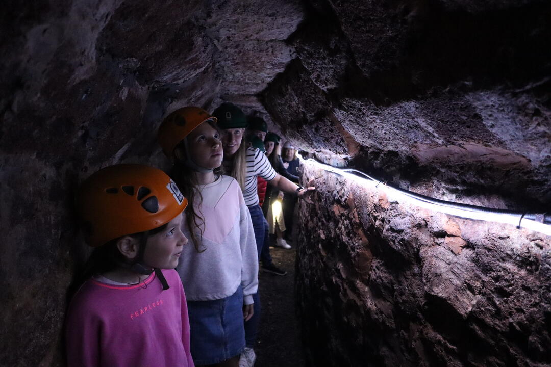 A group of children in helmets exploring an underground passage