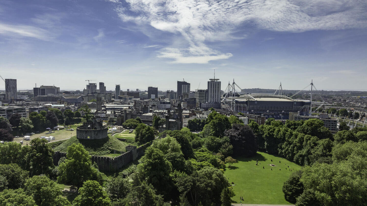 View of Bute Park, Cardiff from above, with green trees in the foreground and blue skies