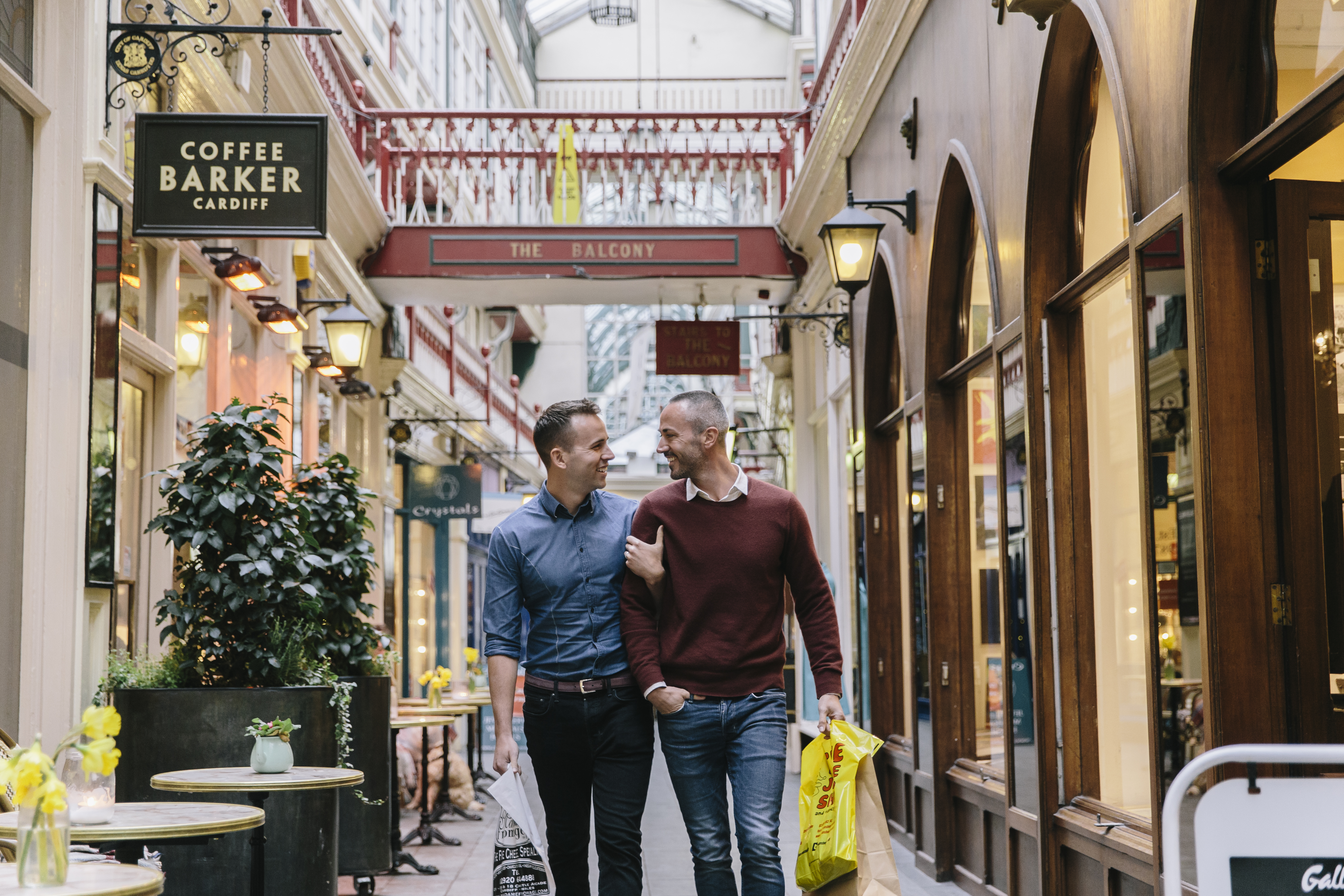 Couple d'hommes marchant bras dessus bras dessous dans une galerie marchande victorienne