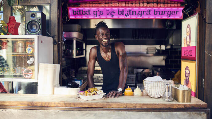 Homme souriant travaillant dans un stand de restauration servant des hamburgers