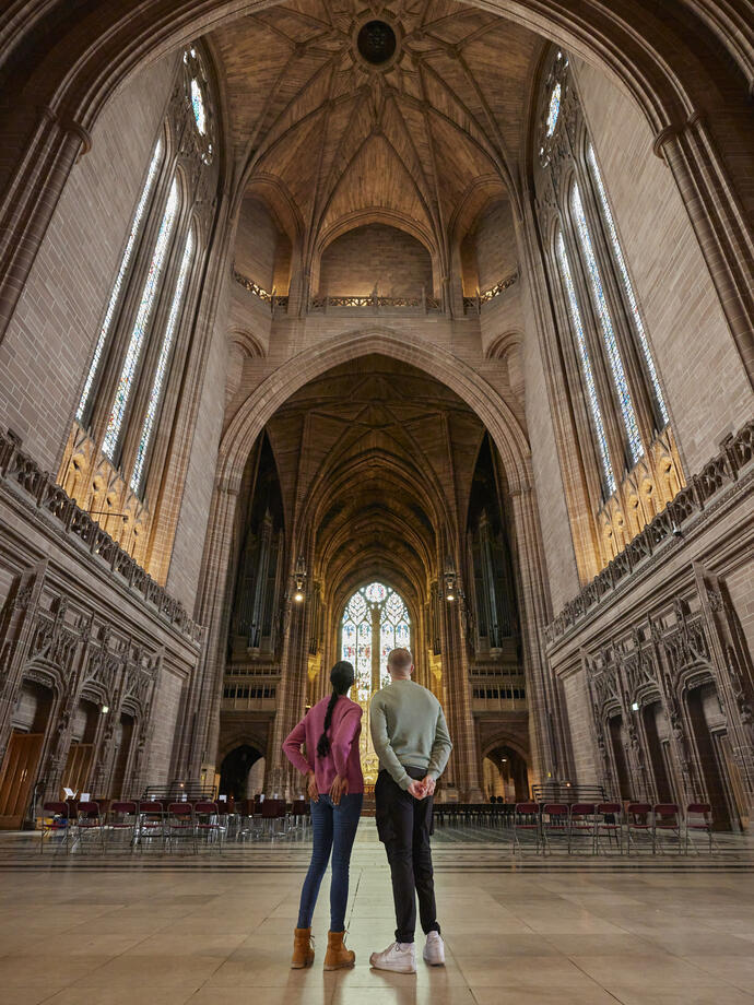 Two people take a tour of an Anglican Cathedral.
