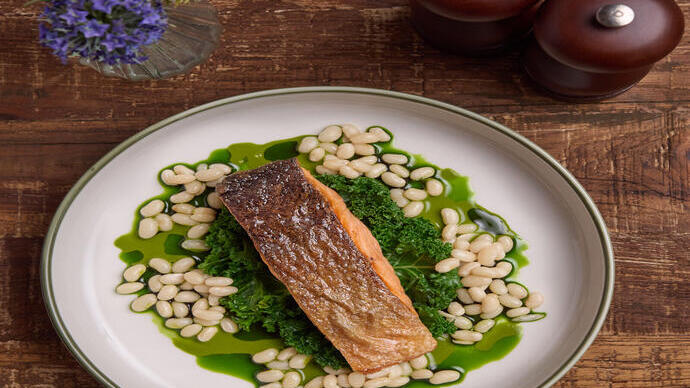 Un plat de poisson sur une feuille de chou frisé et des haricots