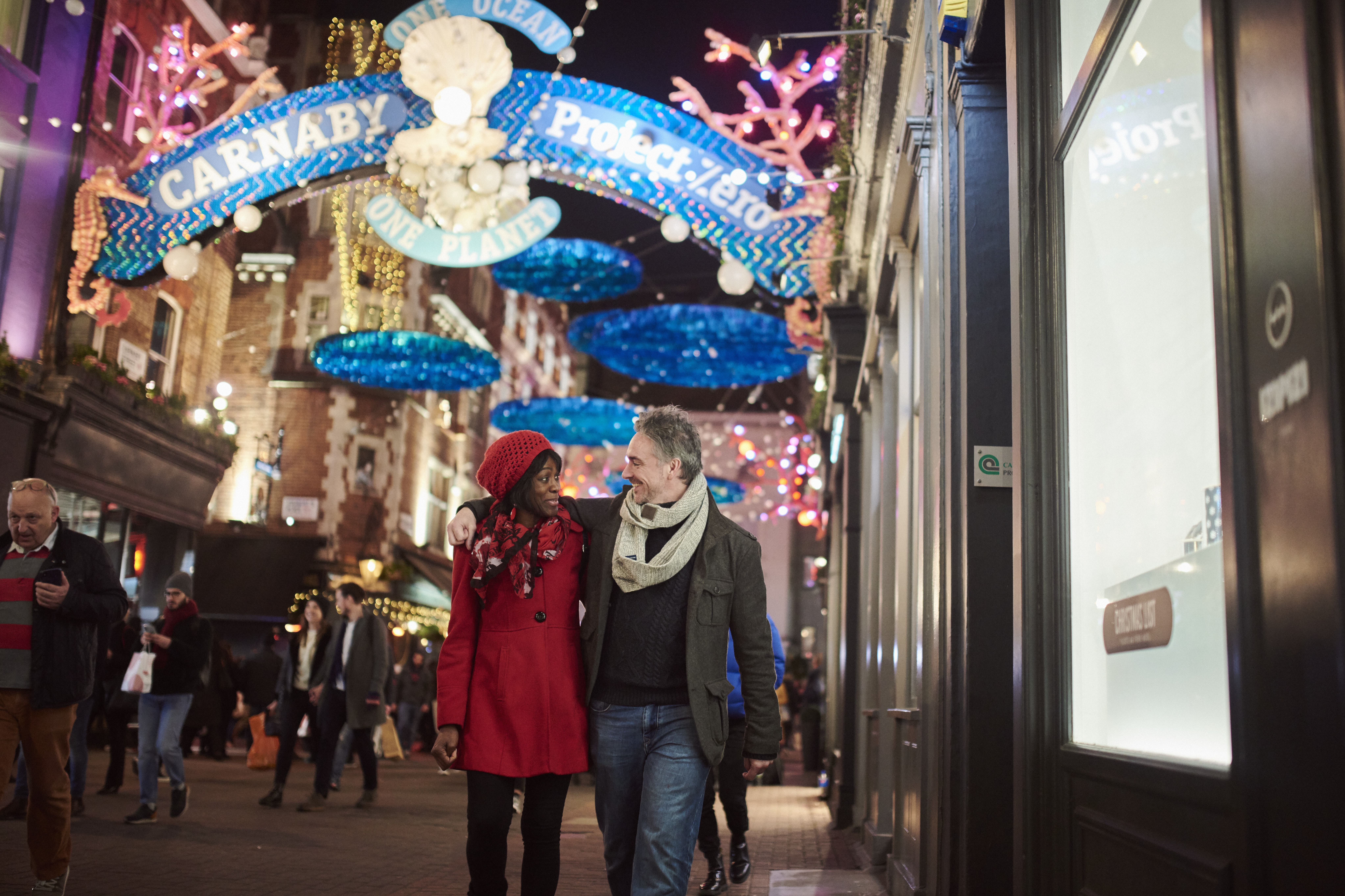 Paar, das unter Weihnachtsbeleuchtung die Straße entlanggeht