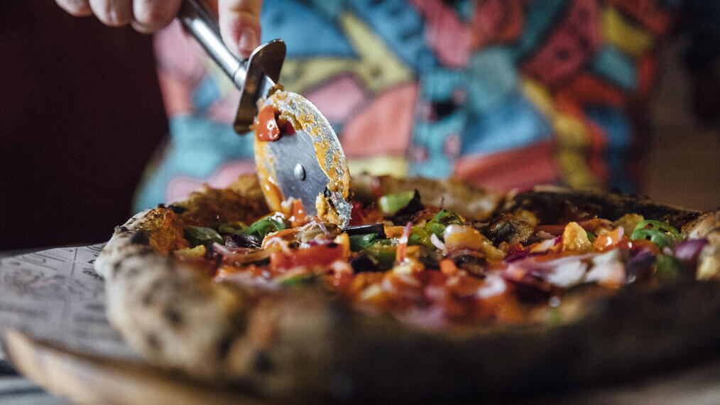 A freshly baked pizza being cut in a restaurant