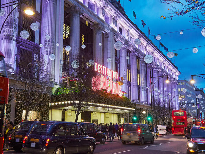 A large department store decorated with Christmas lights on a busy street