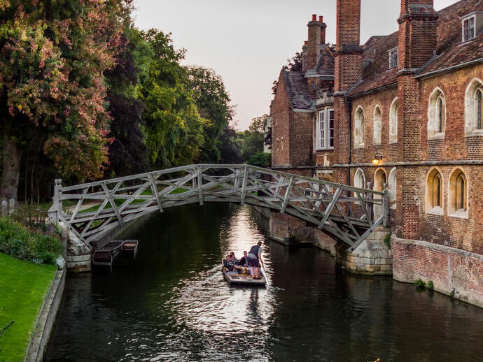 Ein einzelnes Boot fährt unter der Mathematical Bridge in der Silver Street in Cambridge an einem späten Sommerabend hindurch