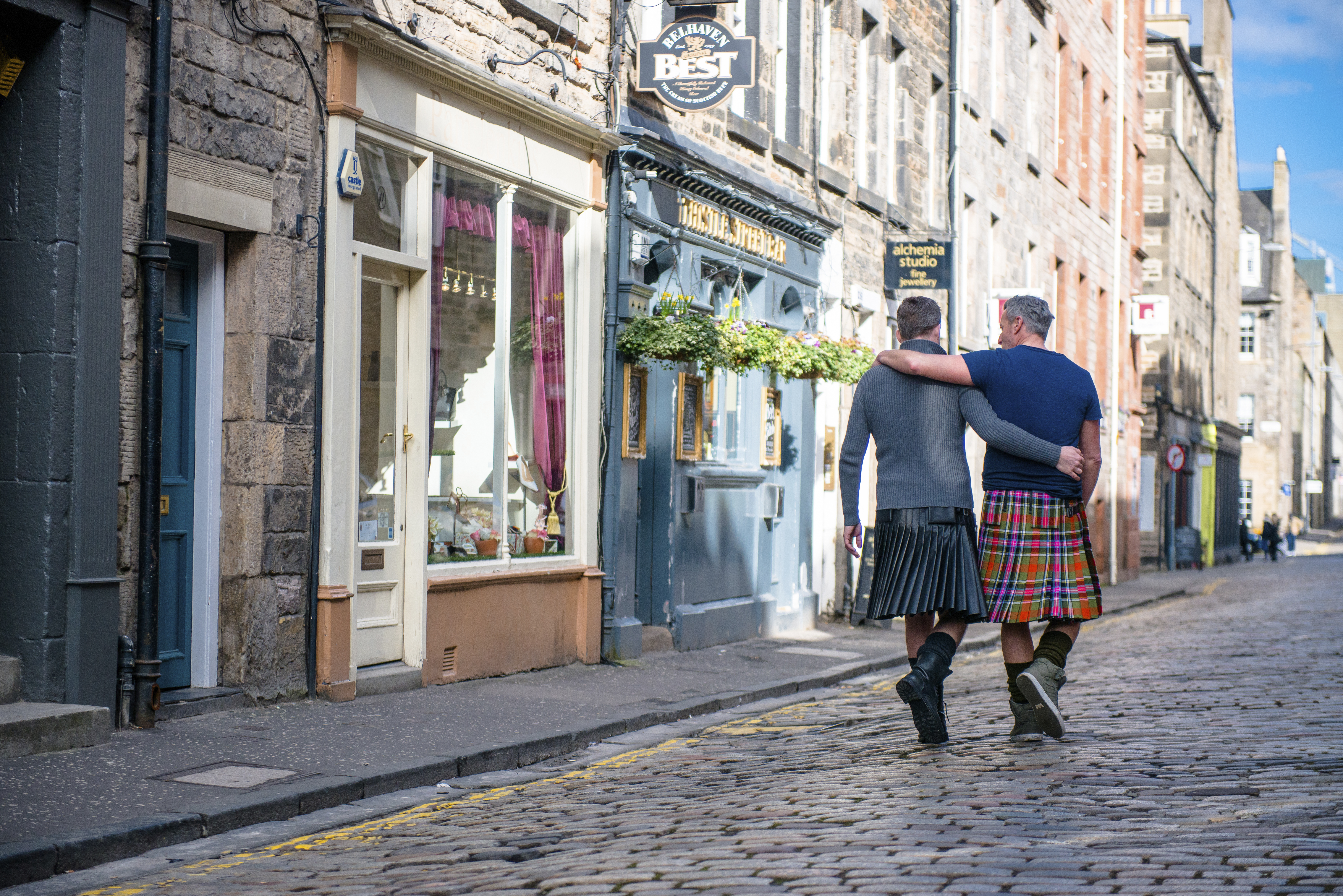 Gleichgeschlechtliches Paar, das Kilts trägt und Arm in Arm geht