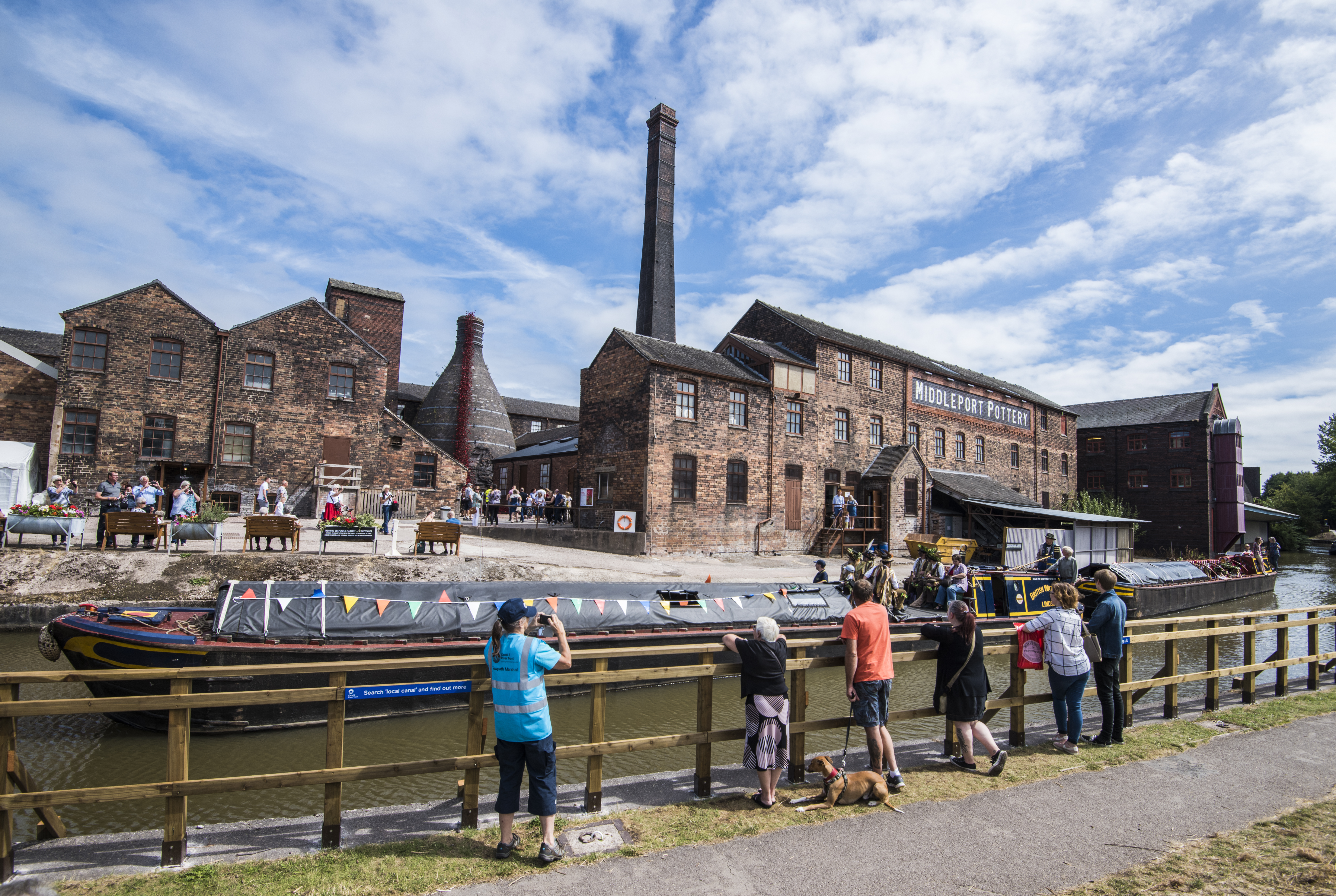 A group of people looking across the Trent and Mersey Canal at several historic buildings in Stoke