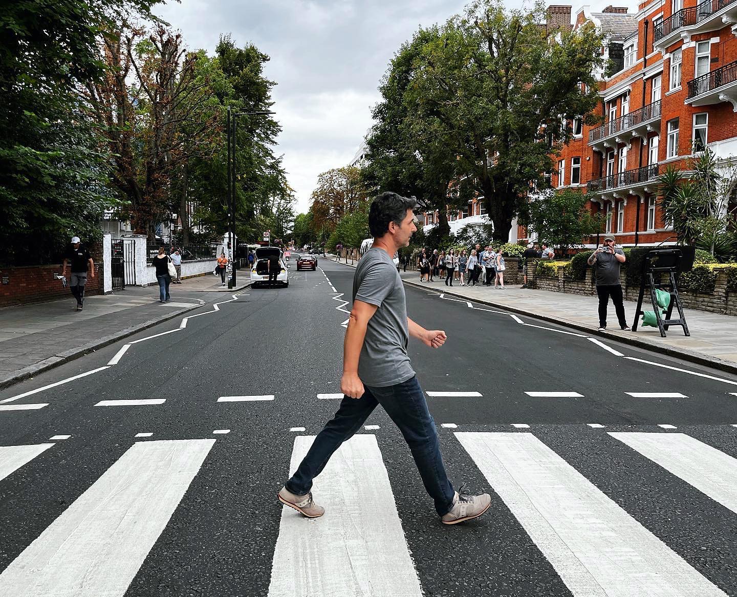 A man crossing the road outside of Abbey Road Studios, a recreation of the famous album cover from The Beatles