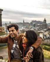 زوجان يلتقطان صورة سيلفي بهاتف محمول مع مدينة في الخلفية