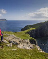 Young walker looking at the view of the ocean from a cliff edge peninsula.
