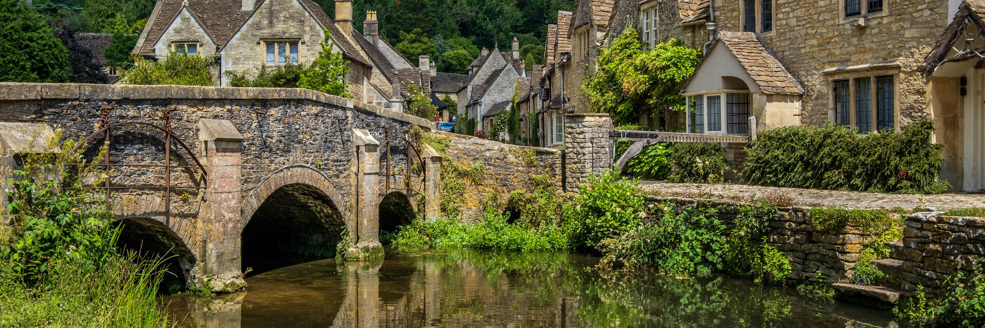 Blauer Himmel und Spiegelungen im malerischen Cotswold-Dorf Castle Combe.