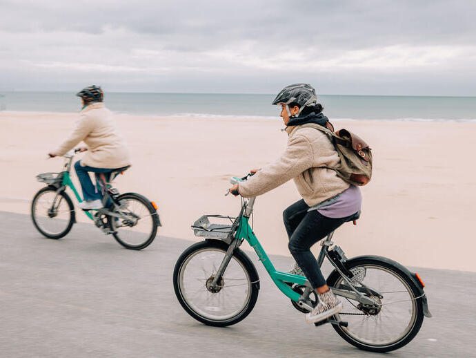 شخصان يركبان الدراجات على شاطئ بورنماوث.