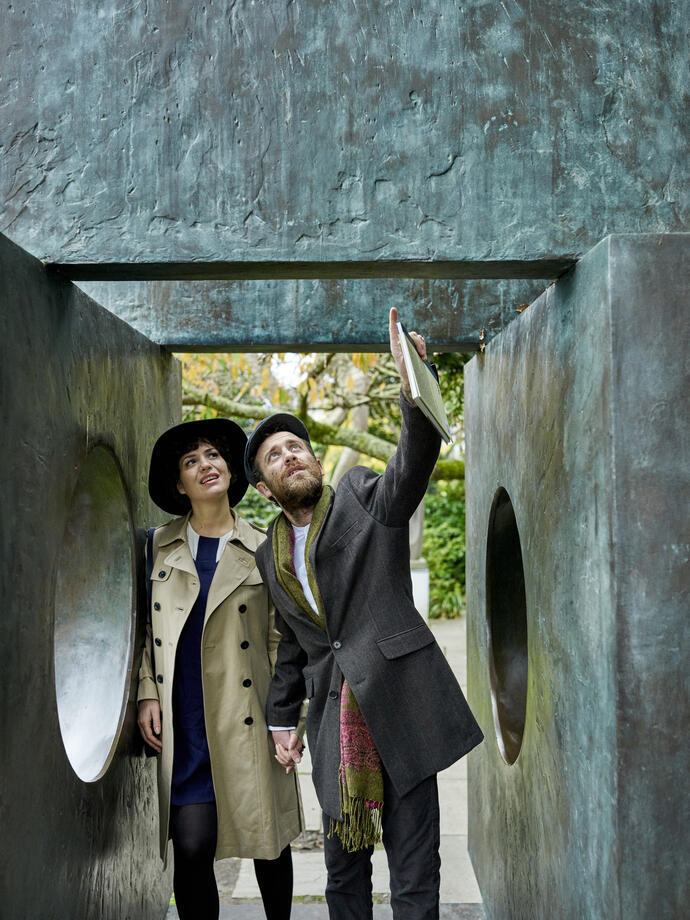 Couple standing next to bronze sculptures and installations in a garden