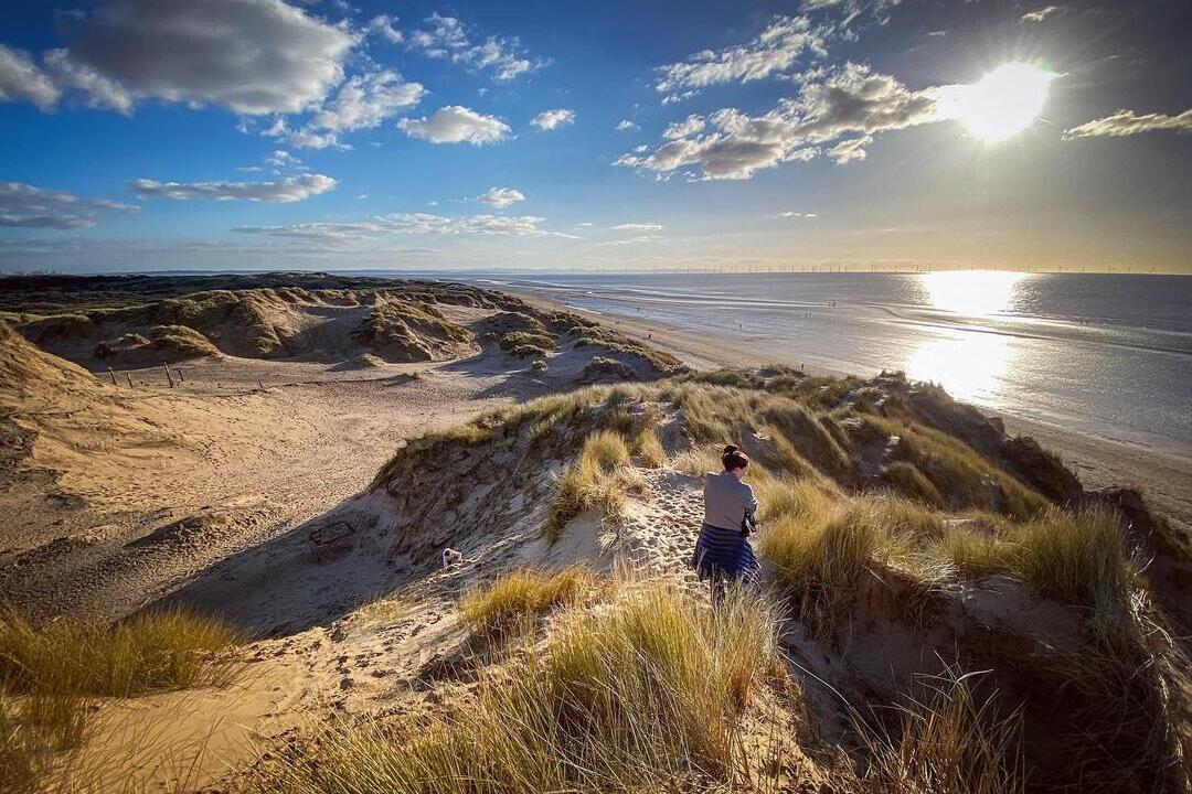 Woman walking along sand dunes at Formby beach