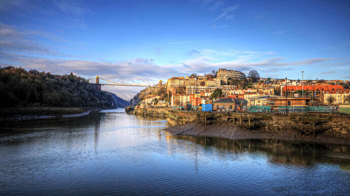 A city on the banks of a river with a large bridge in the distance