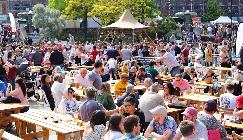 Menschenmengen, die im Rahmen des Sheffield Food Festivals im Freien essen und trinken