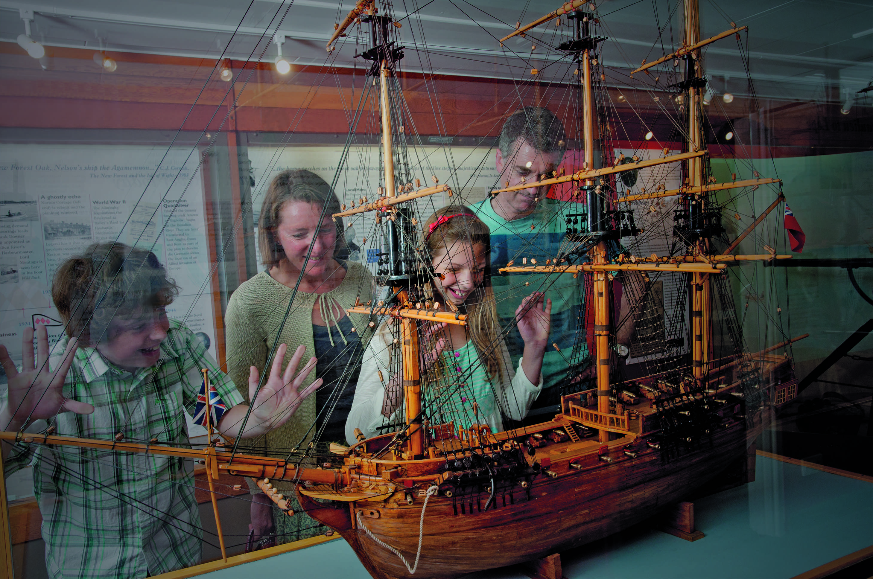 Family with children looking at ancient ship model on display in a museum