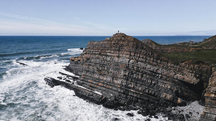A rocky cliff with sea surrounding it