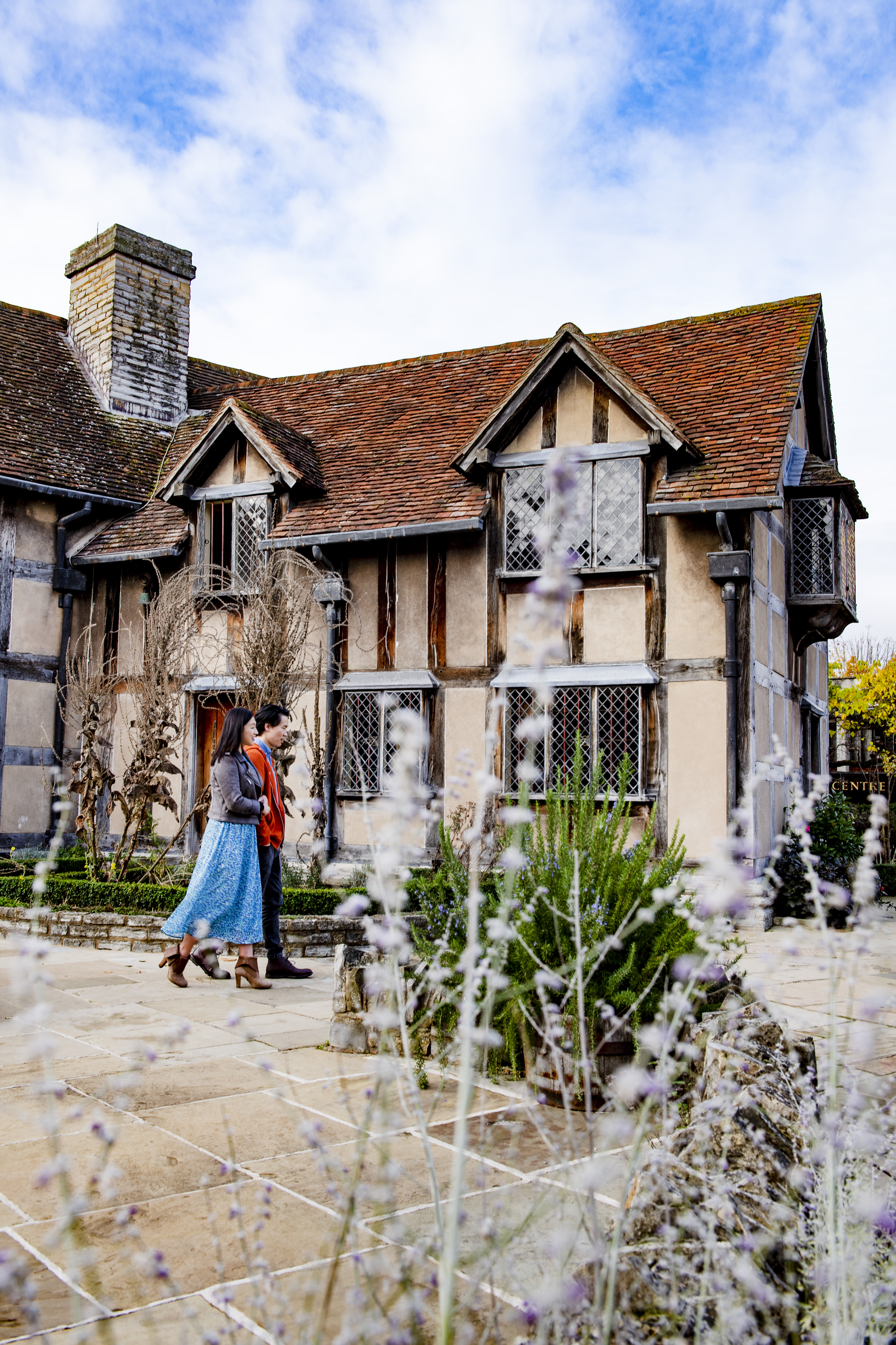 Couple walking through a garden of a Tudor building