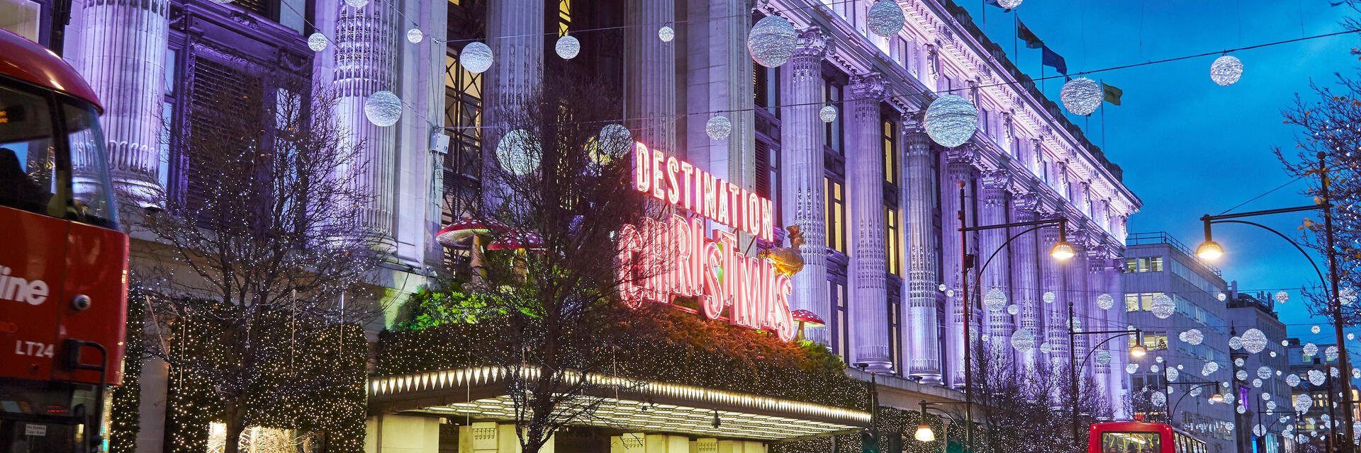 Ein großes Kaufhaus, geschmückt mit Weihnachtsbeleuchtung, in einer belebten Straße