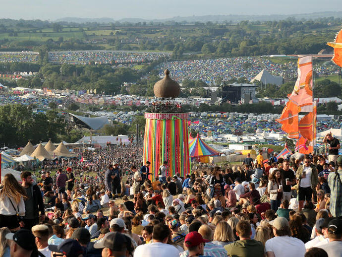 Crowd at Glastonbury Festival sitting on a hill during the day