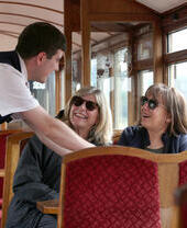 Passeggeri di un treno storico che parlano con un membro dell'equipaggio.