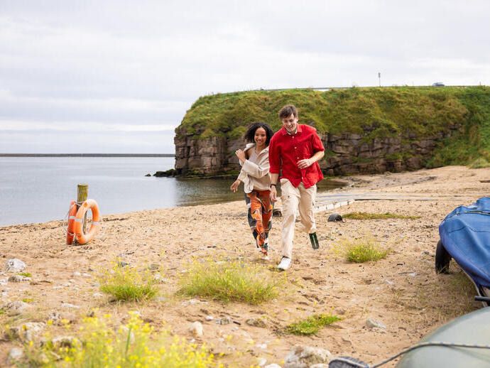 Couple running on the beach, the man has a prosthetic leg