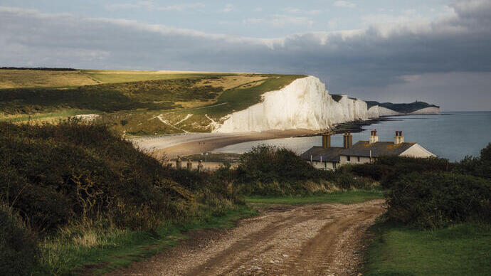 Ferienhäuser an der Küste mit Meer und weißen Klippen im Hintergrund