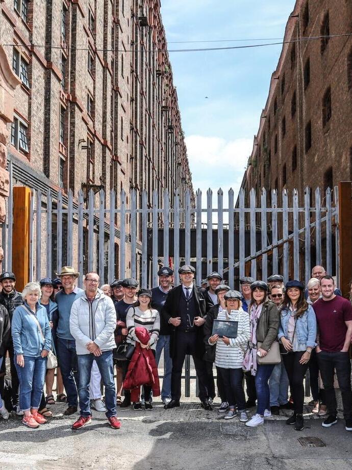 A Peaky Blinders tour group posing outside an industrial warehouse in Liverpool