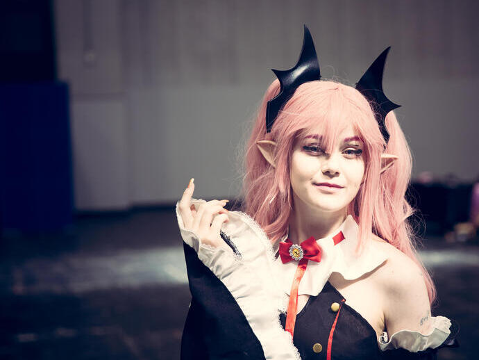 A female cosplayer dressed as a Japanese Anime character with colourful wig and make up at a comic con event