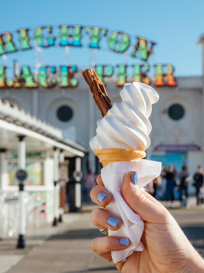Close up of person holding ice cream cone on pier
