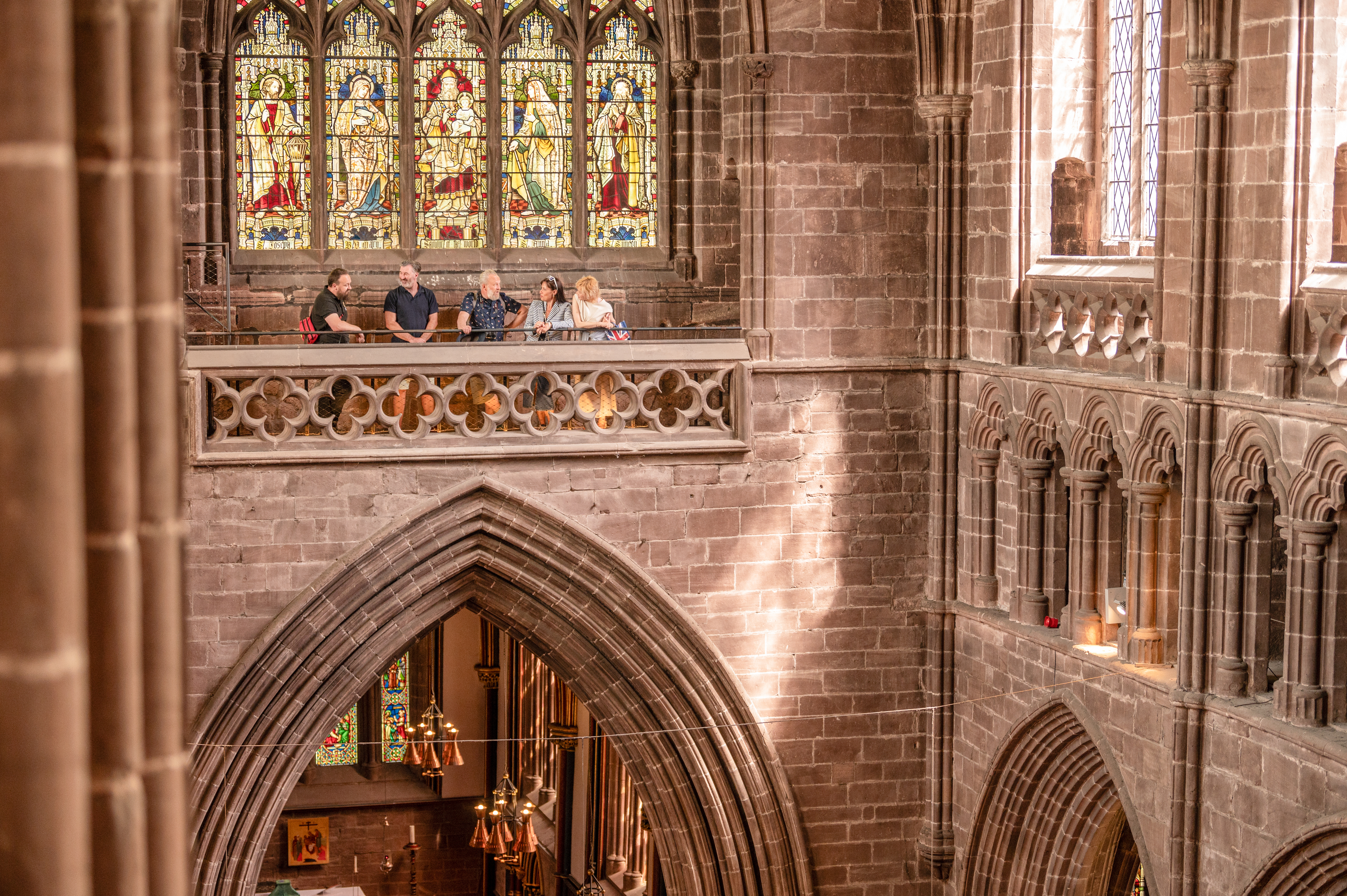 A group of people stand in a viewing platform inside a Cathedral.