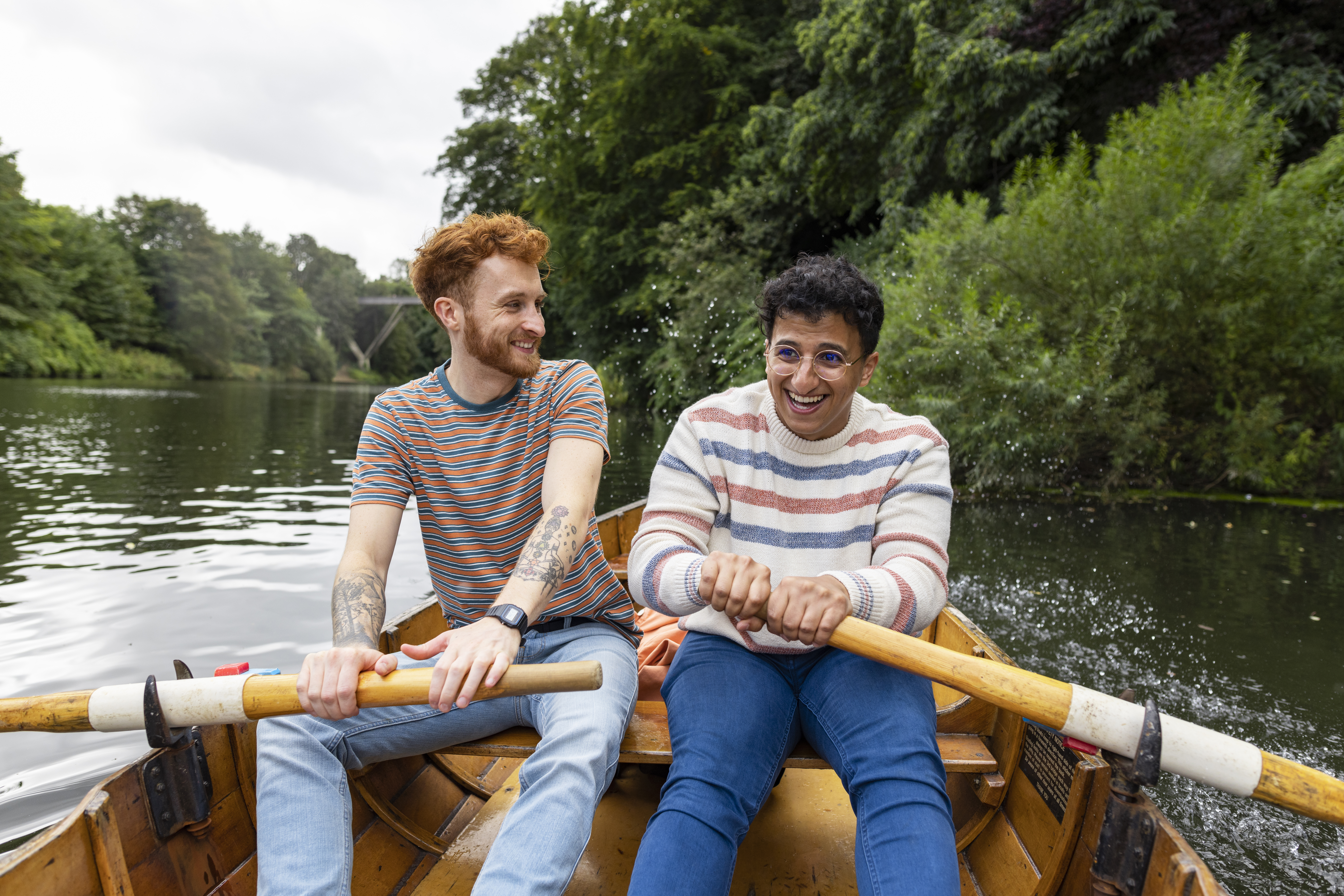 A male couple sitting in a rowboat, rowing together