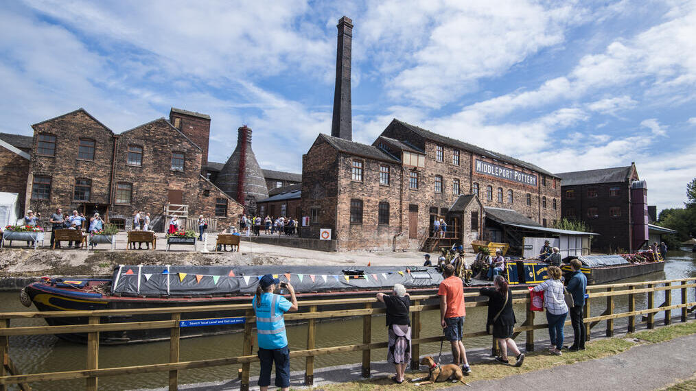 Eine Gruppe von Menschen, die über den Trent and Mersey Canal auf mehrere historische Gebäude in Stoke blicken