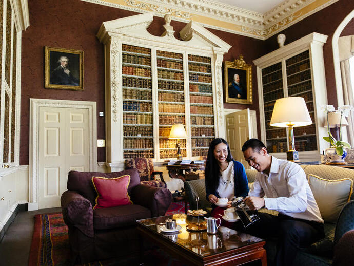 An asian couple, sitting on a sofa, having afternoon tea