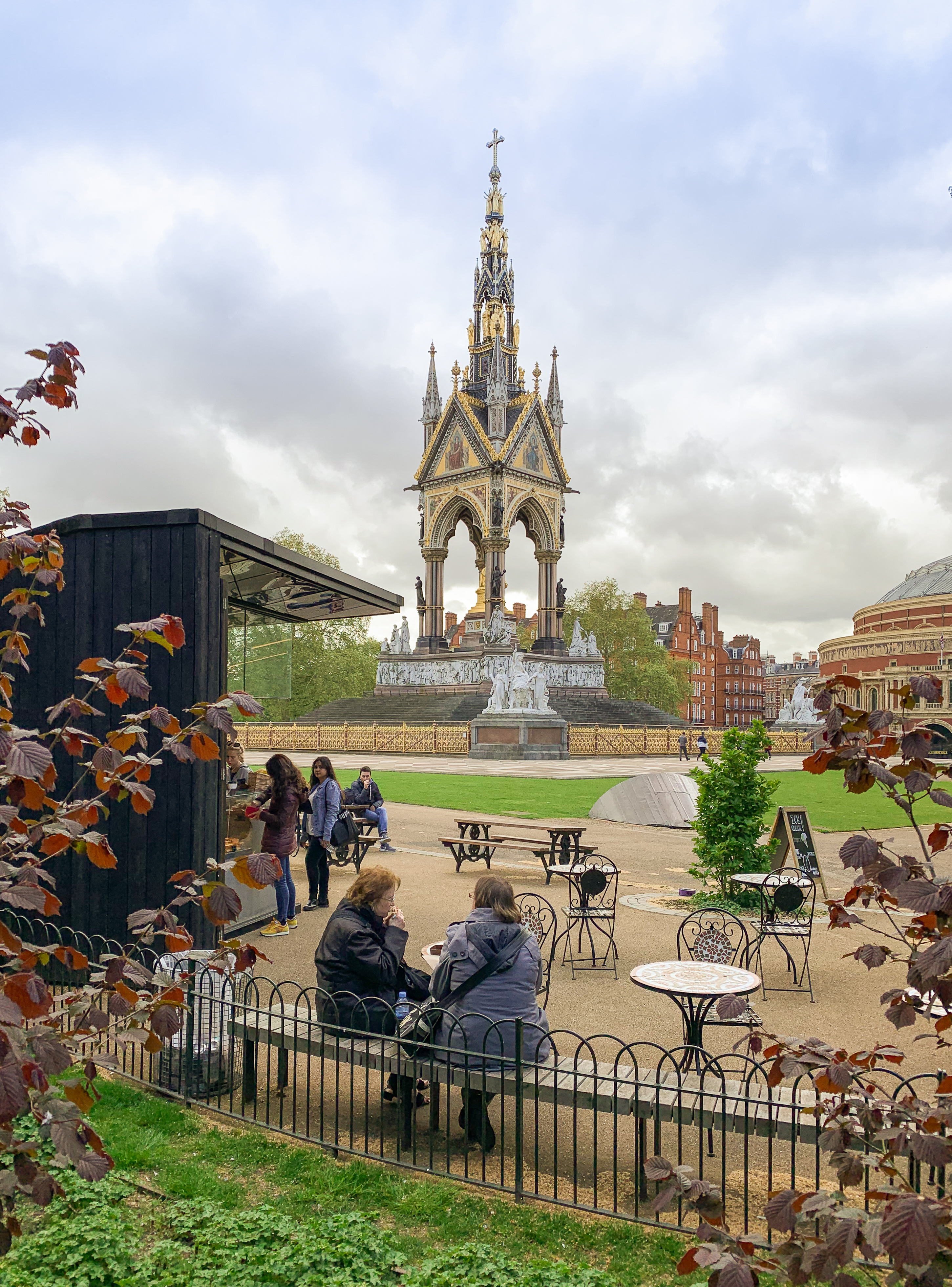 Persone sedute in un giardino all'aperto con vista su un grande monumento commemorativo.