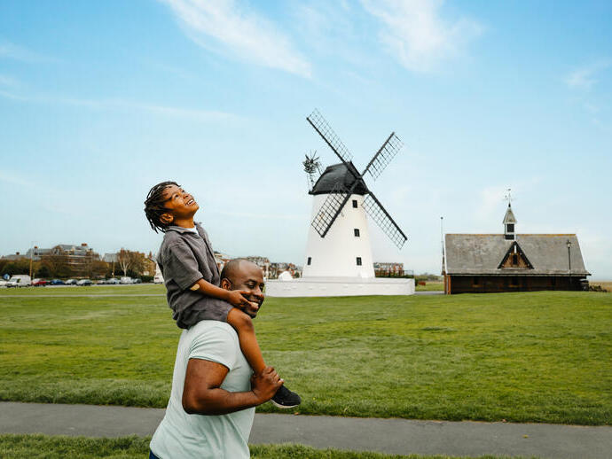 A father and son have fun in a field in front of a windmill