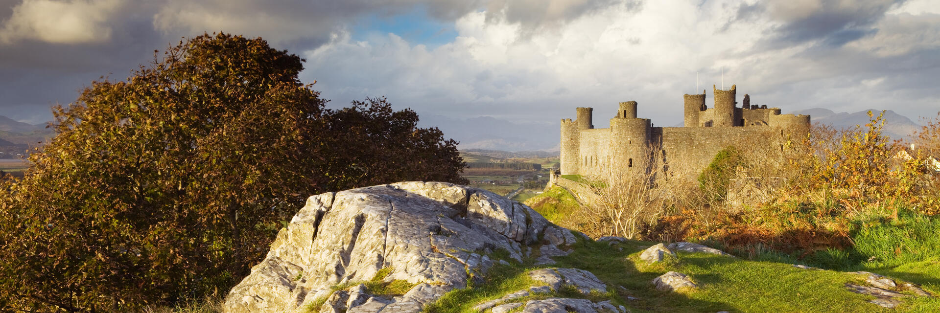 Un château se dressant au sommet d'une colline verdoyante, entouré d'un ciel bleu et de nuages.