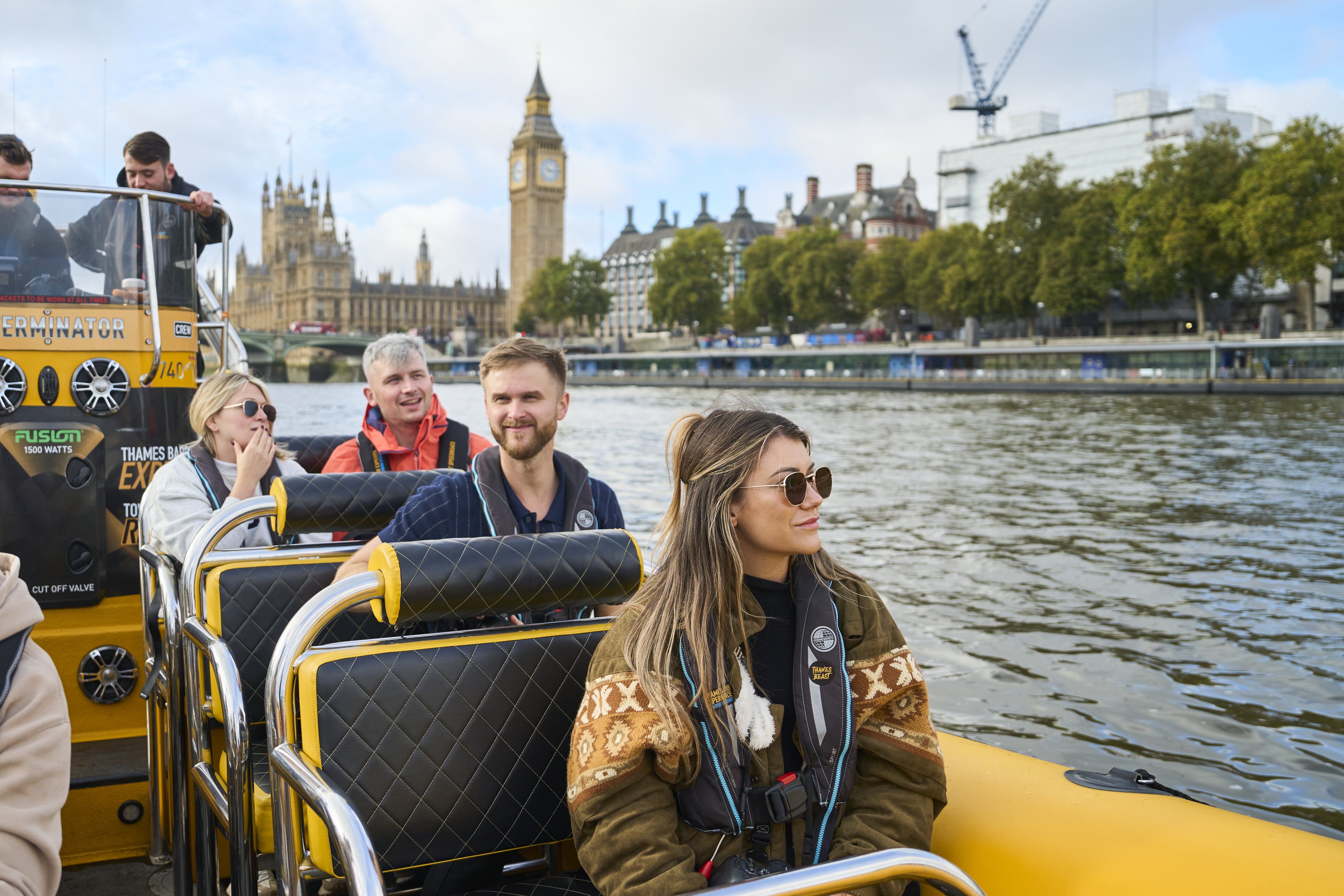 Menschen genießen eine Bootsfahrt auf der Themse in London mit Big Ben und dem Palace of Westminster im Hintergrund.