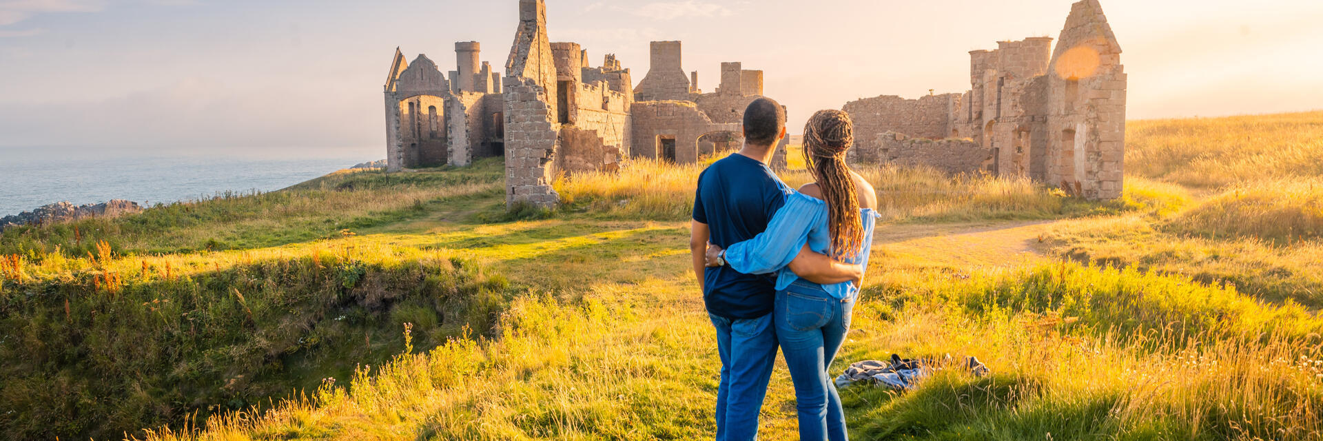 A couple enjoying the views of a castle remains at golden hour.