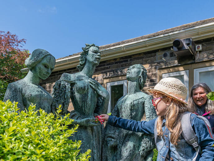 A girl putting flowers into the hands of a statue